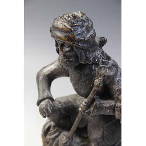 464 - A carved oak hanging figure, circa 1600, carved as a kneeling man holding a staff, upon acanthus car... 