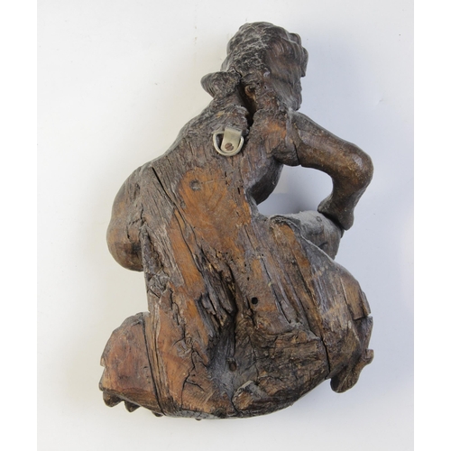 464 - A carved oak hanging figure, circa 1600, carved as a kneeling man holding a staff, upon acanthus car... 