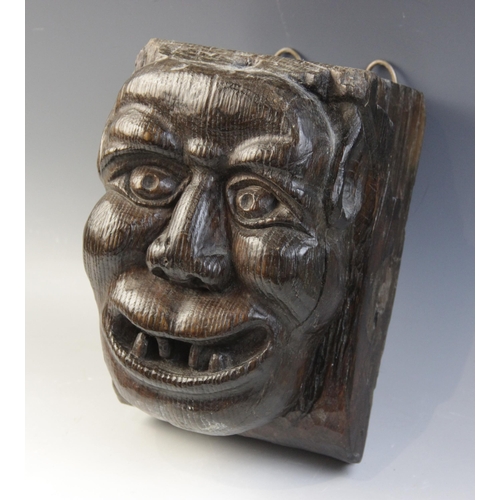 465 - A late 15th century grotesque figural corbel, designed as a male smiling and bearing his teeth, 23.5... 