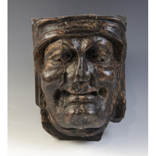 466 - A late 15th/early 16th century carved oak corbel, depicting a male grimacing, 21cm H (excluding late... 