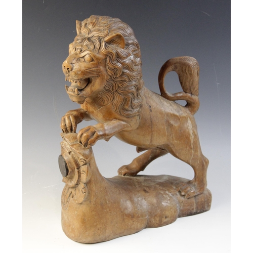 477 - A carved beech figure of a lion, modelled standing with paws upon a stump carved with a rose (later ... 