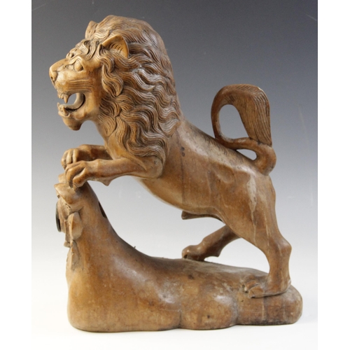 477 - A carved beech figure of a lion, modelled standing with paws upon a stump carved with a rose (later ... 