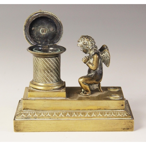 48 - A brass desk inkwell, 19th century, designed as a cherub kneeling before a memorial plinth, surmount... 