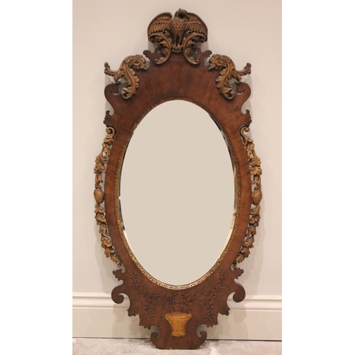 505 - * A 19th century mahogany oval wall mirror, the central mirror plate gilt bordered with carved folia... 