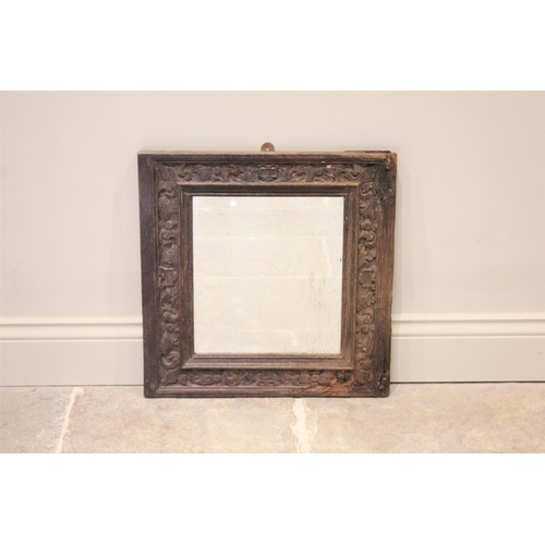 509 - A 17th century and later constructed carved oak mirror, the square frame carved with scrolling folia... 