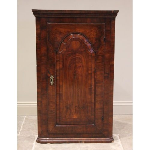 519 - An early 18th century and later, figured walnut hanging corner cupboard, the single straight front f... 