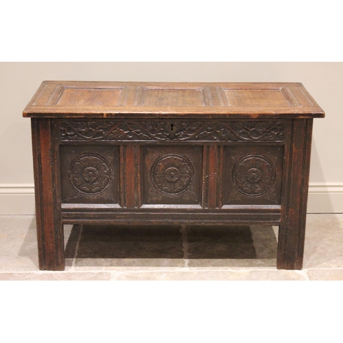 547 - A 17th century oak coffer, the three panel top opening to a fitted candle box, above a frieze carved... 