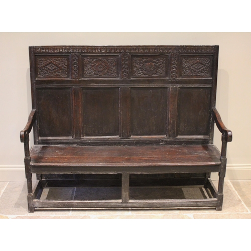 559 - A 17th century and later oak settle, the high back with a nulled frieze over four panels carved with... 