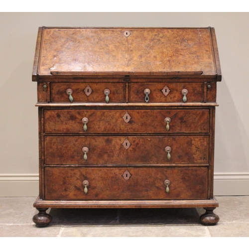 560 - A William and Mary and later figured walnut bureau, in two sections, the feather banded fall front o... 