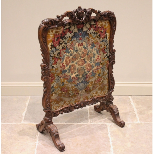 605 - * A French walnut fire screen, 19th century, the Rococo leaf swept carved frame enclosing a needlepo... 