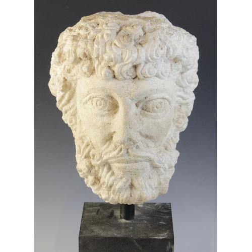 96 - A carved stone head, the male head distinctively carved with curled hair and beard, 29cm high, mount... 