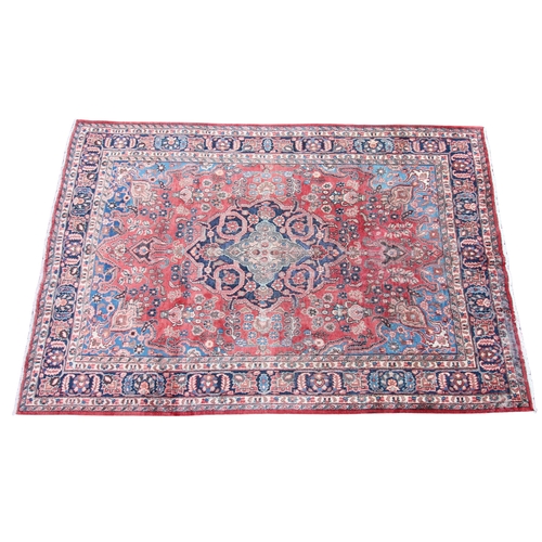 271 - * A Persian pattern wool rug, having a central blue medallion on a red ground, enclosed by foliate u... 