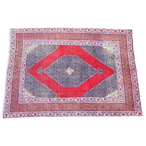 274 - * An Iranian wool rug, the red ground with a central serrated lozenge medallion, enclosed by conform... 