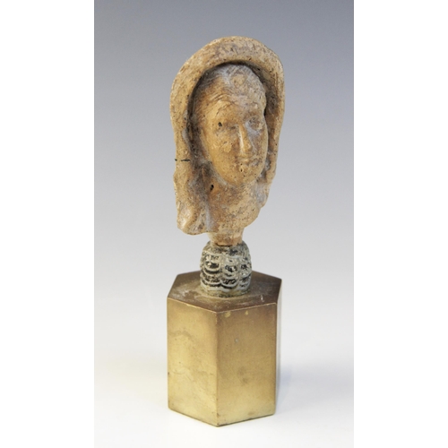 126 - A limestone carved female head depicted wearing a himation partially covering her hair, set into an ... 