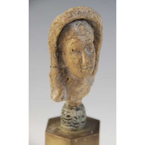 126 - A limestone carved female head depicted wearing a himation partially covering her hair, set into an ... 