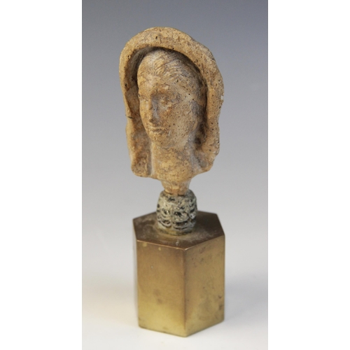 126 - A limestone carved female head depicted wearing a himation partially covering her hair, set into an ... 