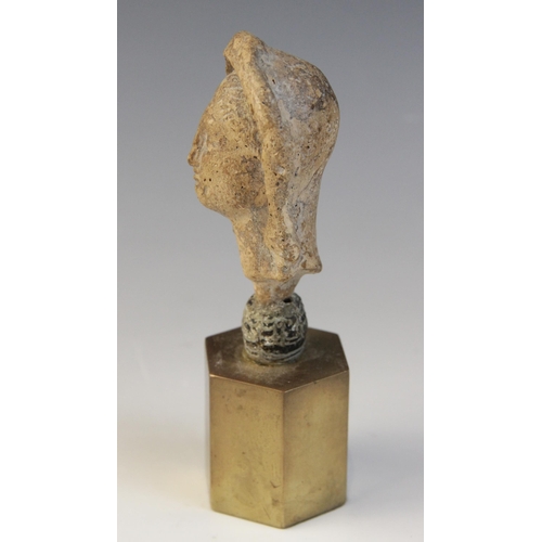 126 - A limestone carved female head depicted wearing a himation partially covering her hair, set into an ... 