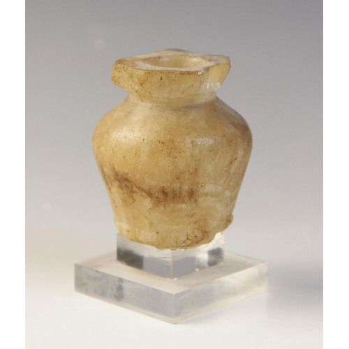 128 - An Egyptian Middle Kingdom alabaster kohl vessel, circa 2000 B.C., 6cm high and a limestone head of ... 