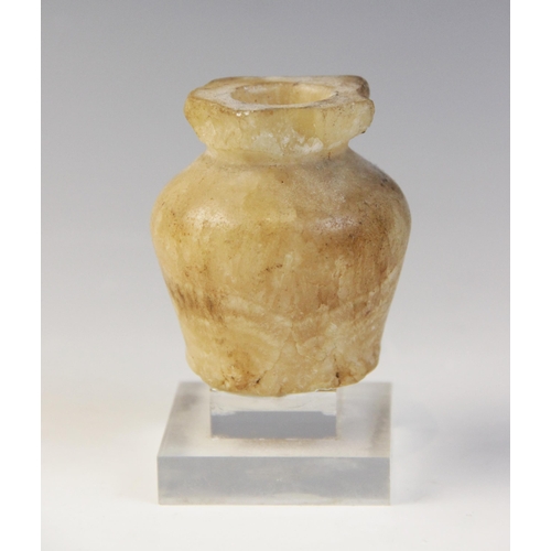 128 - An Egyptian Middle Kingdom alabaster kohl vessel, circa 2000 B.C., 6cm high and a limestone head of ... 