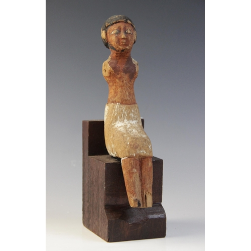 131 - An Egyptian polychrome painted wood model figure, shown seated with arms missing, wearing a short wi... 