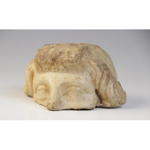 132 - A fragmentary upper half of a head, with carved eyes and wavy hair framing the face, 5cm x 10cm (at ... 