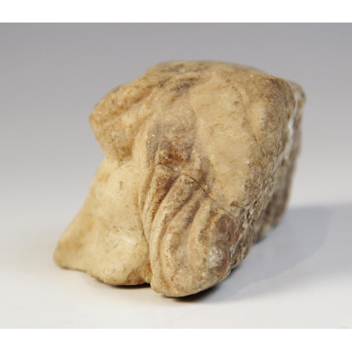 132 - A fragmentary upper half of a head, with carved eyes and wavy hair framing the face, 5cm x 10cm (at ... 