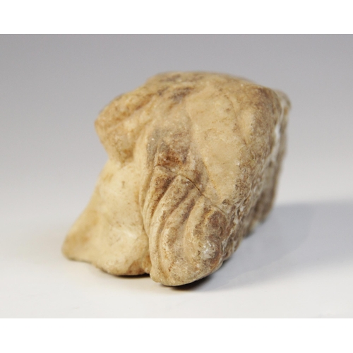 132 - A fragmentary upper half of a head, with carved eyes and wavy hair framing the face, 5cm x 10cm (at ... 