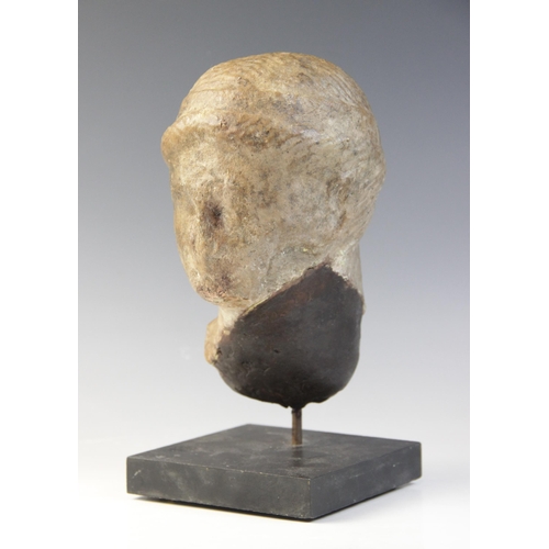 138 - A marble female head, features worn, her hair held in place beneath a fillet, 20cm high (at fault) 
... 