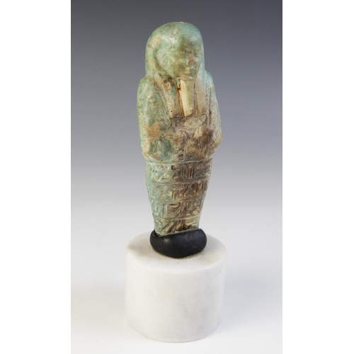 158 - A fragmentary Egyptian green glazed faience shabti, holding two hoes with four horizontal bands of t... 