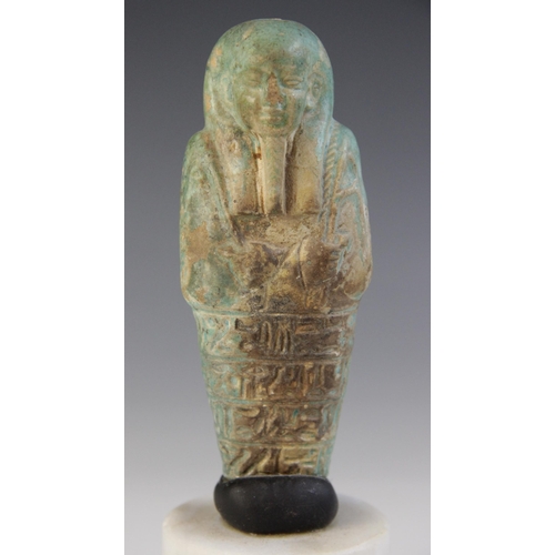 158 - A fragmentary Egyptian green glazed faience shabti, holding two hoes with four horizontal bands of t... 