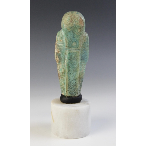 158 - A fragmentary Egyptian green glazed faience shabti, holding two hoes with four horizontal bands of t... 