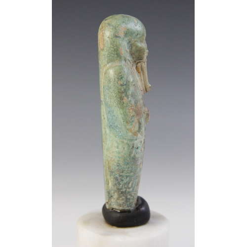 158 - A fragmentary Egyptian green glazed faience shabti, holding two hoes with four horizontal bands of t... 