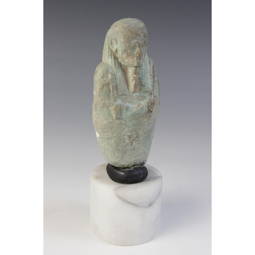 159 - A fragmentary Egyptian blue glazed faience shabti, holding a pick and a hoe, worn bands of horizonta... 