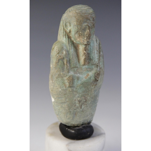 159 - A fragmentary Egyptian blue glazed faience shabti, holding a pick and a hoe, worn bands of horizonta... 