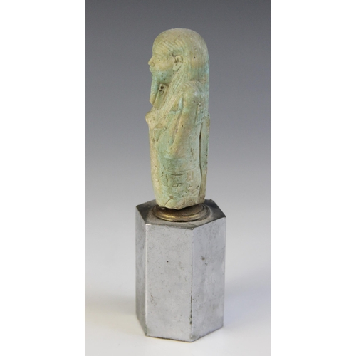 160 - A fragmentary Egyptian green glazed faience shabti, holding a pick and hoe with the remains of two h... 