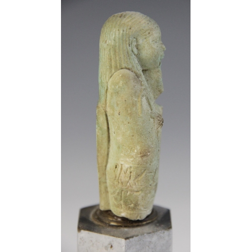 160 - A fragmentary Egyptian green glazed faience shabti, holding a pick and hoe with the remains of two h... 