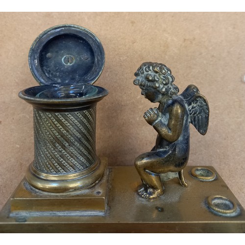 48 - A brass desk inkwell, 19th century, designed as a cherub kneeling before a memorial plinth, surmount... 