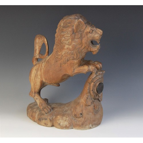 477 - A carved beech figure of a lion, modelled standing with paws upon a stump carved with a rose (later ... 