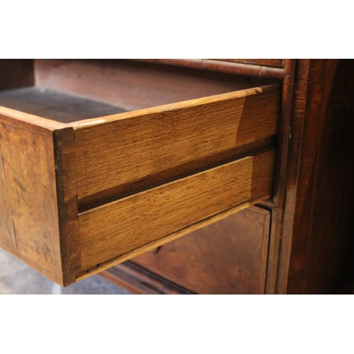 560 - A William and Mary and later figured walnut bureau, in two sections, the feather banded fall front o... 