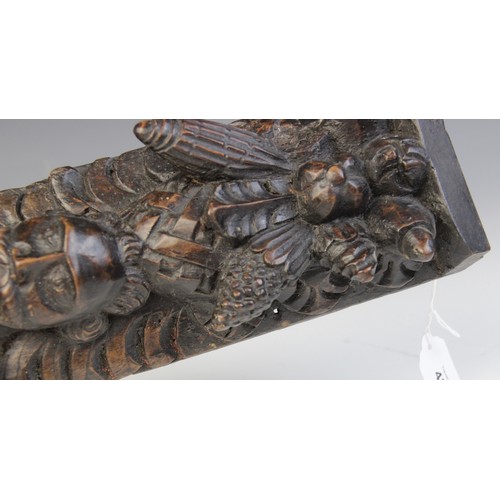 438 - An early 17th century carved walnut term, circa 1630, carved with a male holding a bird, atop a lion... 