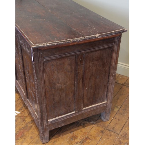 525 - An early 17th century tall oak coffer, the twin board top with a moulded rim, above a frieze carved ... 