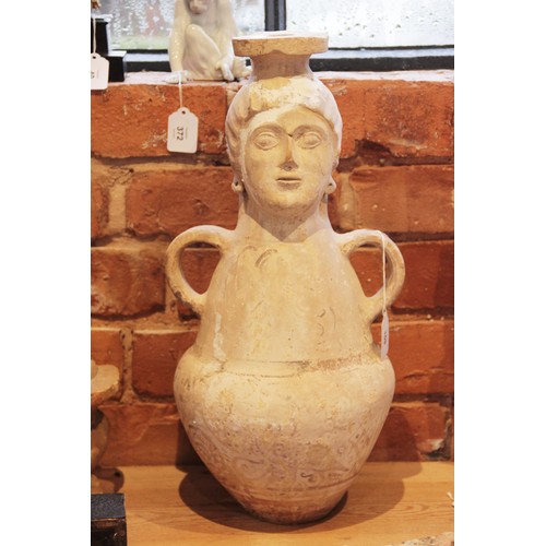 108 - A terracotta water jug, the amphora form jug with loop handles, the neck modelled as a head with fla... 