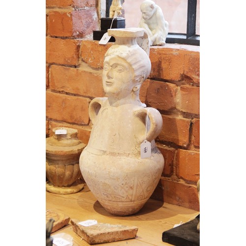 108 - A terracotta water jug, the amphora form jug with loop handles, the neck modelled as a head with fla... 