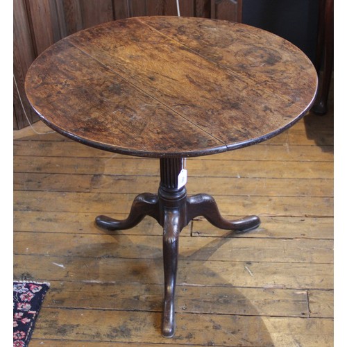 582 - A George III tripod table, the circular oak three plank top, raised upon an associated fluted column... 