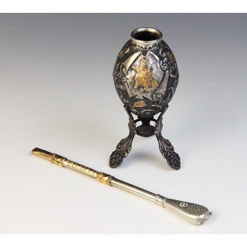 107 - A silver coloured Yerba and Bombilla, the egg shaped Yerba on three raised feet with central cartouc... 