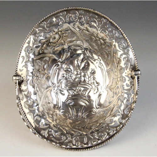 24 - A George III silver swing handled sweetmeat basket, of oval form with pierced and repoussé decoratio... 