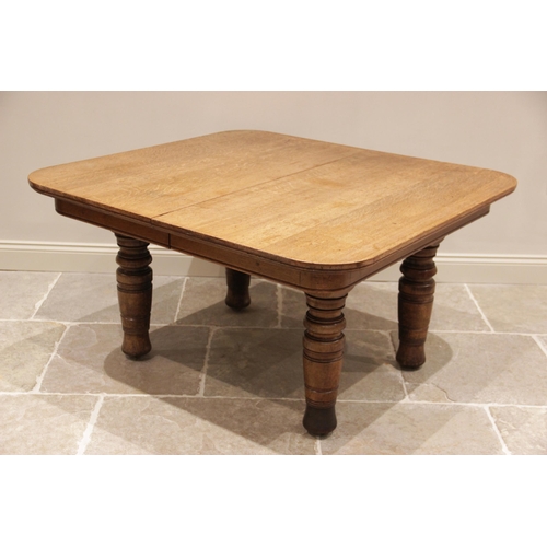 707 - A late Victorian honey oak extending dining table, the rectangular top with rounded corners raised u... 