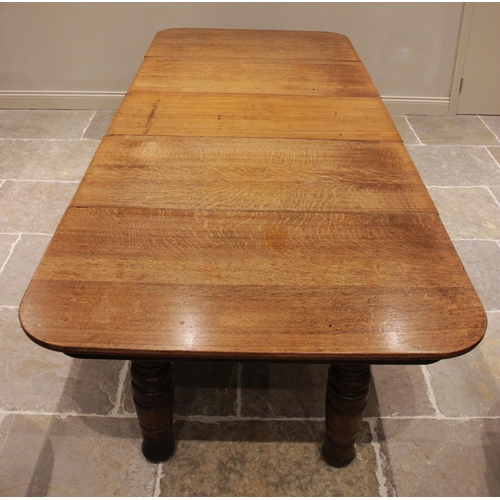 707 - A late Victorian honey oak extending dining table, the rectangular top with rounded corners raised u... 