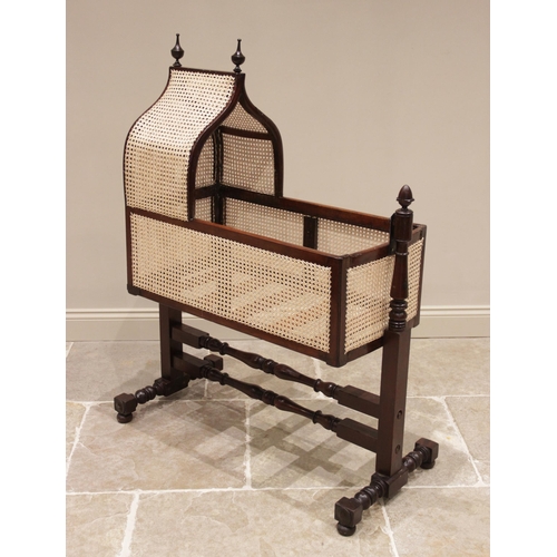 709 - A Victorian mahogany and rattan cradle, the ogee shaped canopy with turned finials above rattan side... 