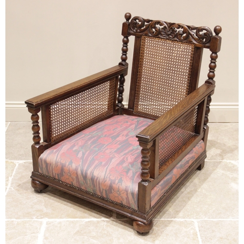 726 - An early 20th century oak bergere armchair, later re-covered in Liberty style fabric, the scrolling ... 